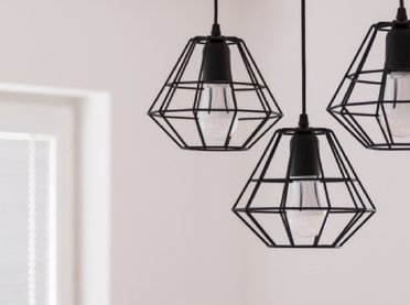 Three wired black lampshades hanging from the ceiling